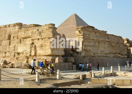 Gizeh, Ägypten, November 17 2018: Touristen an der Stelle der Pyramiden von Gizeh um Ruinen einer Steinmauer und die Spitze der großen Pyramide von Gizeh Stockfoto