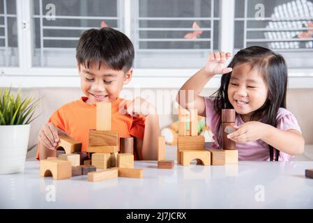 Glückliche kleine Kinder spielen Holzblock Stapeln Brettspiel zu Hause, Kinder Junge und Mädchen spielen mit Konstruktor Holzblock, Kindheitsaktivitäten lernen Stockfoto