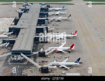 Heathrow Airport Terminal 2 Luftaufnahme, auch bekannt als Queen's Terminal. Vielbeschäftigter Flughafenterminal in Großbritannien mit mehreren Flugzeugen. Stockfoto