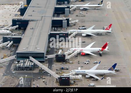 Heathrow Airport Terminal 2 Luftaufnahme mit mehreren Langstreckenflugzeugen, die an den Düsenbrücken für Passagiere an Bord geparkt sind. Flughafen von oben. Stockfoto