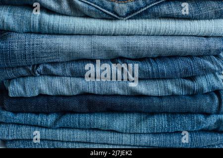 Der Stapel des Stapels der alten Jeans verschiedene Schattierungen der blauen Jeans. Denim-Jeans-Struktur. Denim-Hintergrundtextur für Design. Denim-Struktur in Canvas. Blauer Denim Stockfoto