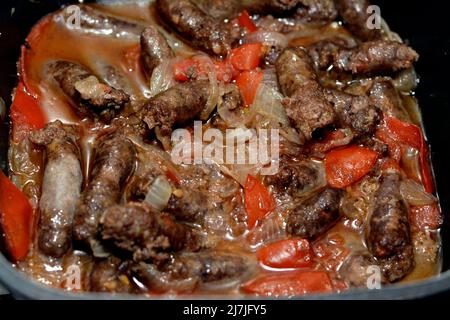 Selektive Konzentration von gekochter Rinderwurst im Kochtopf mit geschnittenen Tomaten, Zwiebeln, Knoblauch, Salz, Gewürzen, Kreuzkümmel und kleine Menge Öl auf heißen s gekocht Stockfoto