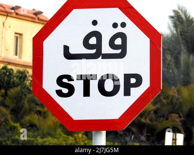 Zweisprachiges arabisches und englisches STOPPSCHILD Tafel mit arabischer Textskript und englischer Übersetzung (Stop) mit einer Achteck-Form, einem Straßenverkehrssymbol für ein Stockfoto