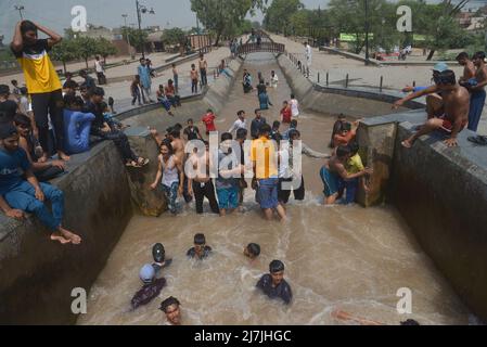 Lahore, Pakistan. 08.. Mai 2022. Die pakistanischen Menschen kühlen sich in einem Kanal während des heißen Wetters in lahore ab. Im März und April versengte extreme Hitze den Großteil Indiens und des benachbarten Pakistans, wodurch über eine Milliarde Menschen Temperaturen von weit über 40 Grad Celsius (104 Fahrenheit) ausgesetzt waren. Die wärmsten Monate des Jahres stehen noch bevor. (Foto von Rana Sajid Hussain/Pacific Press) Quelle: Pacific Press Media Production Corp./Alamy Live News Stockfoto