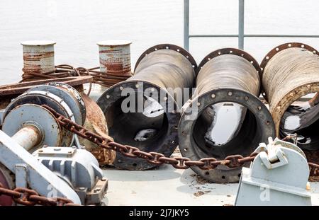 Rustikale Ankermaschine und gelagerte verlassene Rohre auf einem Baggerschiff aus nächster Nähe Stockfoto
