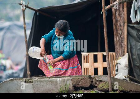 Bogota, Kolumbien 9. Mai 2022. Eine indigene Frau überträgt Wasser in eine Flasche, als die indigenen Gemeinden der Embera das provisorische Lager verlassen, das vor 8 Monaten errichtet wurde, wo mehr als 1000 durch Konflikte vertriebene indigene Menschen lebten und Vereinbarungen mit der Regierung getroffen haben, an einen nahe gelegenen Ort vor der Rückkehr in ihre Territorien überführt zu werden, In Bogota, Kolumbien, 9. Mai 2022. Foto: Chepa Beltran/Long Visual Press Stockfoto