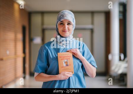 Hannover, Deutschland. 29. April 2022. Die Intensivpflegerin Farah Hareb-Demir hält das Buch „Nowhere a Country“ auf dem Campus der Medizinischen Hochschule Hannover (MHH) in der Hand. In dem Buch beschreibt die Krankenschwester ihre Geschichte zusammen mit der Journalistin Menkens. Hareb-Demir lebt seit mehr als 30 Jahren in Deutschland, doch trotz mehrerer Gerichtsverfahren und eines unbefristeten Arbeitsvertrags droht ihr die Ausländerbehörde weiterhin mit Abschiebung. (To dpa 'unklare Identität: Intensivkrankenschwester immer noch nur toleriert') Quelle: Ole Spata/dpa/Alamy Live News Stockfoto