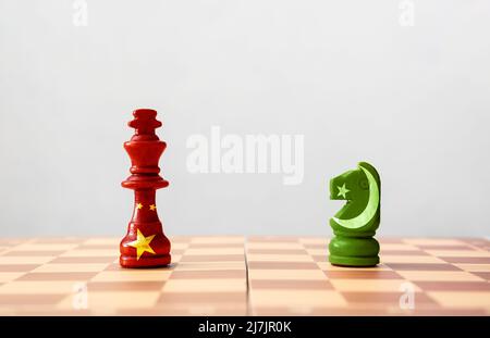 Schachfiguren in Farben chinesischer und pakistanischer Flaggen auf Schachbrett vor hellem Hintergrund Stockfoto