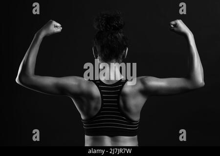 Schwarz-Weiß-Foto einer sportlichen jungen afroamerikanischen Frau auf dunklem Hintergrund Stockfoto