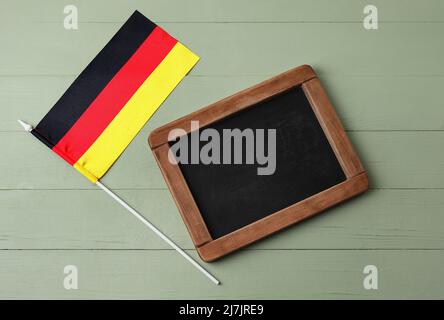 Flagge Deutschlands und Tafel auf farbigem Holzhintergrund Stockfoto