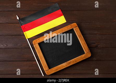 Flagge Deutschlands und Tafel auf dunklem Holzhintergrund Stockfoto