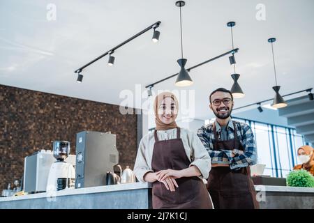 muslimische Kellnerin und Partnerportrait lächeln vor der Kamera Stockfoto