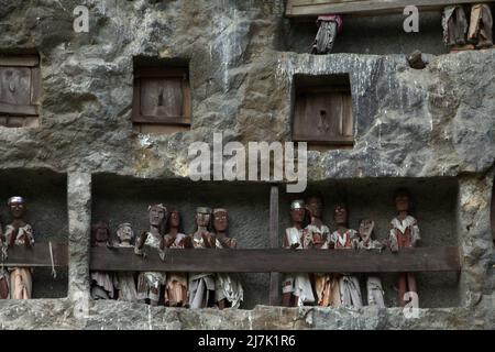 Steingrabeöffnungen und Holzraster auf einer Klippe an einer traditionellen Grabstätte in Lemo, Nord-Toraja, Süd-Sulawesi, Indonesien. Stockfoto