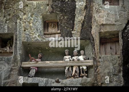 Steingrabeöffnungen und Holzraster auf einer Klippe an einer traditionellen Grabstätte in Lemo, Nord-Toraja, Süd-Sulawesi, Indonesien. Stockfoto