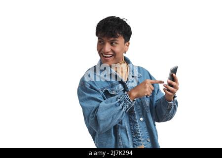 Ein junger peruanischer Mann zeigte glücklich und isoliert auf seinen Telefonbildschirm. Stockfoto