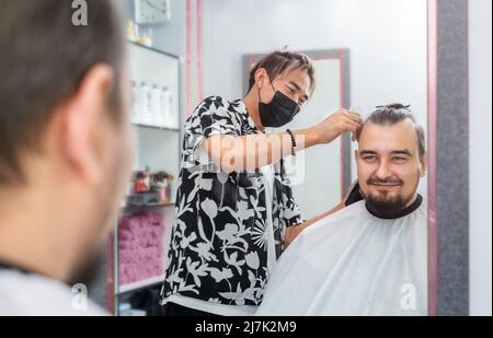 Der Friseur schneidet im Friseursalon auf der Spiegelei Männerhaare Stockfoto