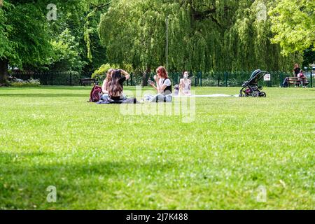 Epsom Surrey, London, Mai 09 2022, Gruppen junger Menschen sitzen auf dem Gras in Einem Park, entspannen und reden Stockfoto