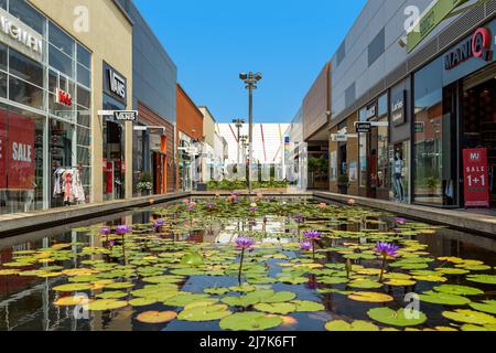 Künstlicher Teich mit Blumen zwischen Geschäften und Boutiquen im Open-Air-Einkaufszentrum in Ashdod, Israel. Stockfoto