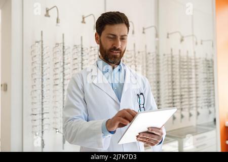 Augenarzt mit Brillen mit digitalem Tablet während der Arbeit im optischen Geschäft Stockfoto