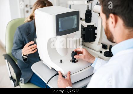 Der männliche Augenarzt überprüft die Sehkraft eines Patienten in einem Augenarztgeschäft oder in einer Augenklinik Stockfoto
