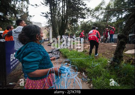 Eine indigene Mutter von Embera hilft Mitgliedern des Sozialamts von Bogota, einen Schuppen abzubauen, während die indigenen Gemeinden von Embera beginnen, den provisorischen Notdienst zu verlassen Stockfoto