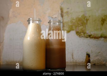 Milchshake-Schokoladenmilch in Flaschen mit Trinkhalmen mit Vintahe-Hintergrund Stockfoto