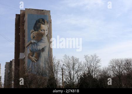 Künstlerisch bemaltes Haus, Wolkenkratzer, der nach dem Himmel greift riesiges Mädchen und Teddybär an der Hauswand, Wandmalerei. Stockfoto