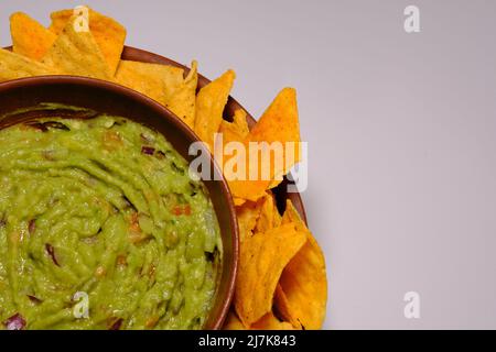 Mexikanische Guacamole-Sauce und Tortilla-Chips auf einem isolierten weißen Hintergrund. Guacamole Schüssel mit Nachos Chips. Ort für Text, Nahaufnahme eines Teils t Stockfoto