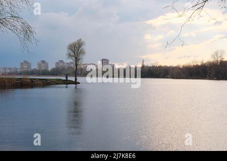 Fischer bei Sonnenuntergang auf dem städtischen See cheha in Sumy, Ukraine. Schöne reflektieren vom Himmel und Wolken im Wasser Stockfoto