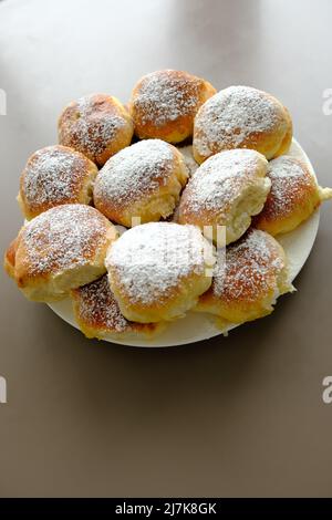 Hausgemachte, altmodische Apfelknödel oder Pasteten auf einem weißen Teller und braunem Hintergrund. Gebacken nach Ukraine Rezept. Stockfoto