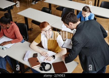 Hochwinkelporträt eines männlichen Professors, der Studenten im College-Klassenzimmer hilft, Raum zu kopieren Stockfoto