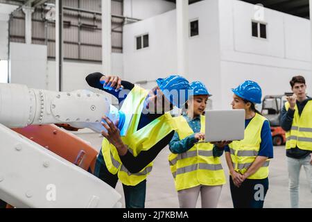 Multiethnische Ingenieure arbeiten in der Automatisierungs- und Roboteranlage zusammen - Neues Industrietechnologiekonzept Stockfoto
