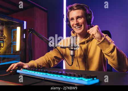 Profi-Gamer mit professionellen Kopfhörern fühlen sich vom Sieg bei Online-Turnieren sehr gepustet. Mann Influencer Blogger Streaming mit Mikrofon, während der Wiedergabe von Computer-Videospiel auf leistungsstarken Computer Stockfoto