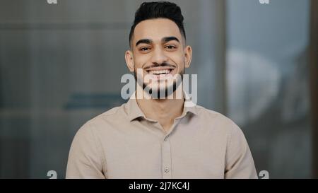 Glücklicher junger Mann hispanisch schöner Mann mit toothy Lächeln Blick auf Kamera männlich Gesicht Porträt Geschäftsmann lächelnd arabischen professionellen Manager Stockfoto