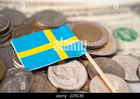 Stapel von Münzen mit Schwedenflagge auf US-amerikanischen Dollar-Banknoten. Stockfoto