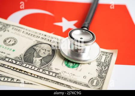 Schwarzes Stethoskop mit US-Dollar-Banknoten auf türkischem Hintergrund, Geschäfts- und Finanzkonzept. Stockfoto