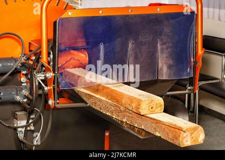 Leistungsstarker industrieller elektrischer Holzhacker mit Holzstämmen, der für die Herstellung von Hackschnitzeln, Holzbriketts und Gartenmulcharbeiten verwendet wird. Stockfoto