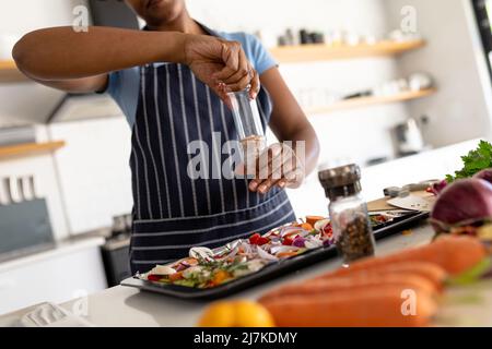 Mittelteil der afroamerikanischen mittleren erwachsenen Frau mit der Zubereitung von Essen in der Küche zu Hause Stockfoto