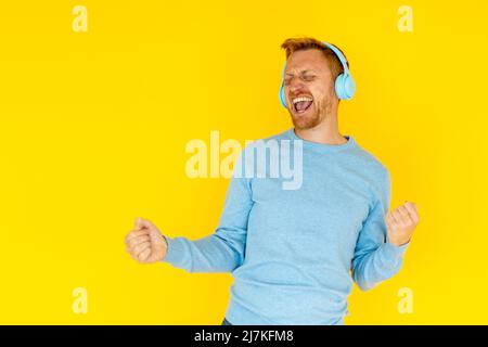Glücklicher junger erwachsener hispanic Latino Mann, der vor gelbem Hintergrund tanzt Stockfoto