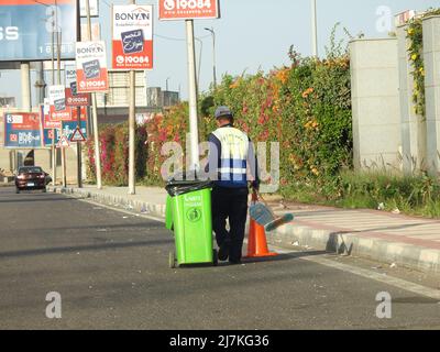 Kairo, Ägypten, November 12 2021: Ein Garbagemann in Schutzkleidung, der mit einem Mülleimer läuft und Müll sammelt, um Müll für die Umwelt zu entfernen Stockfoto