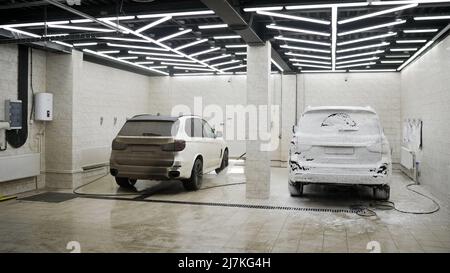 Auto in den Schaum bei der Waschanlage. Wasch schwarzen Auto mit Active-Schaum. Autowäsche. Stockfoto