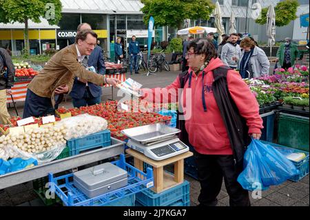 29. April 2022, Nordrhein-Westfalen, Köln: Hendrik Wüst, Spitzenkandidat der CDU für die Landtagswahl, verteilt Werbematerial auf dem Kölner Markt am Neptunplatz. (To dpa 'Frikadelle mit Kakao - wie Wüst und Kutschaty Wahlkampf machen') Foto: Henning Kaiser/dpa Stockfoto