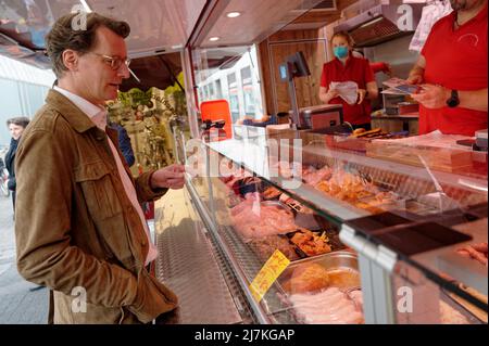 29. April 2022, Nordrhein-Westfalen, Köln: Hendrik Wüst, Spitzenkandidat der CDU für die Landtagswahl, kauft einen Fleischball auf dem Kölner Markt am Neptunplatz. (To dpa 'Frikadelle mit Kakao - wie Wüst und Kutschaty Wahlkampf machen') Foto: Henning Kaiser/dpa Stockfoto