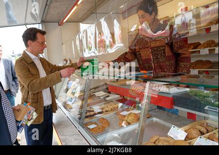 29. April 2022, Nordrhein-Westfalen, Köln: Hendrik Wüst, Spitzenkandidat der CDU für die Landtagswahl, kauft auf dem Markt am Neptunplatz in Ehrenfeld, Köln, ein Gebäck. (To dpa 'Frikadelle mit Kakao - wie Wüst und Kutschaty Wahlkampf machen') Foto: Henning Kaiser/dpa Stockfoto