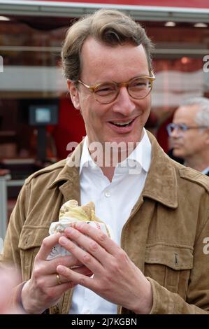 29. April 2022, Nordrhein-Westfalen, Köln: Hendrik Wüst, Spitzenkandidat der CDU für die Landtagswahl, isst auf dem Kölner Markt am Neptunplatz einen Fleischball. (To dpa 'Frikadelle mit Kakao - wie Wüst und Kutschaty Wahlkampf machen') Foto: Henning Kaiser/dpa Stockfoto