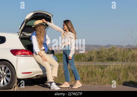 Fröhliche Freundinnen, die in der Mitte des nichts herumspielen und Spaß haben, bei einem Zwischenstopp auf ihrem Roadtrip in der Pausenpause Stockfoto