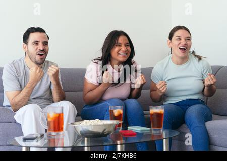 Freunde sehen sich zu Hause gemeinsam Sport im Fernsehen an Stockfoto