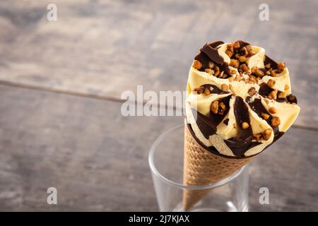 Eis-Kegel aus Vanille und Schokolade auf einem Holztisch Stockfoto