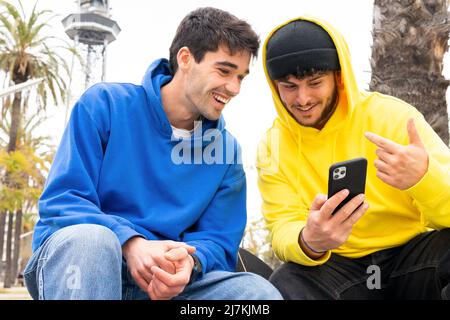 Zwei fröhliche Freunde mit farbenfrohen Outfits, die auf der Straße telefonieren Stockfoto