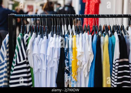 Metallgestell mit verschiedenen T-Shirts und Pullovern an Kleiderbügeln in einer modernen Modeboutique Stockfoto